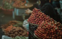 热闹的户外市场摊位上，篮子里装满了成熟的草莓