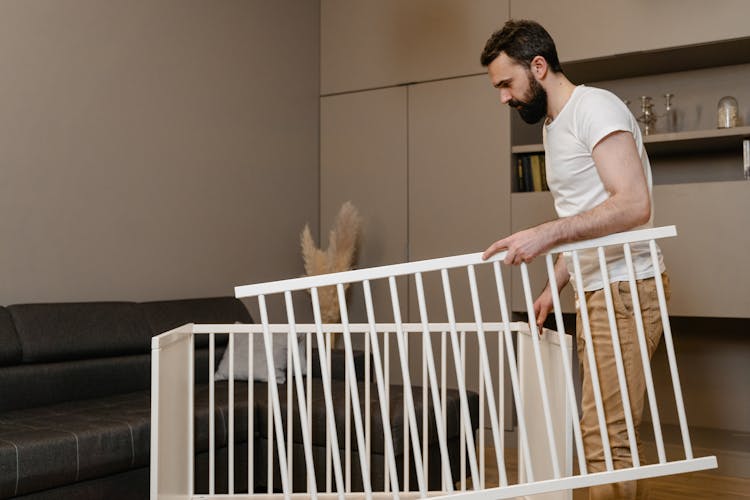 Man Setting Up A Dismantled Baby Crib