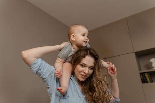 Free A Low Angle Shot of a Woman Carrying Her Baby on Her Shoulders Stock Photo