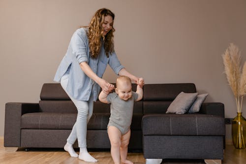 Happy Mother Guiding her Toddler to Walk 