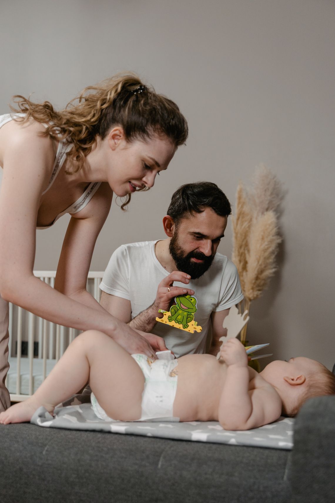 Joyful parents caring for their baby indoors, with the adults' faces clearly visible