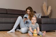 Woman in Gray Long Sleeve Shirt Sitting Beside Girl in Gray Long Sleeve Shirt