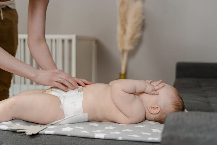 A Parent Changing The Diaper Of A Baby