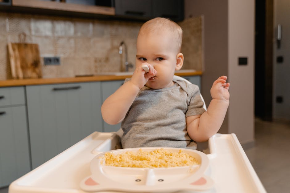 Does Beaba Babycook Actually Save Time at Weaning? Adorable baby in onesie feeding themselves in a high chair indoors.