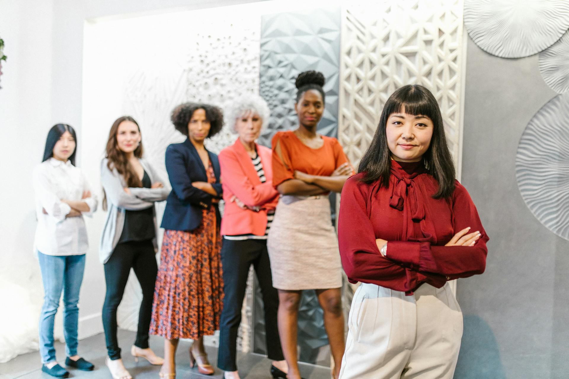 A diverse group of confident business women standing in a modern office setting.