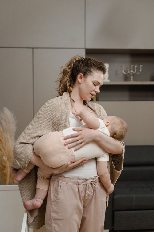 Free A mother lovingly cradles her baby in a serene indoor environment, creating a precious bond. Stock Photo