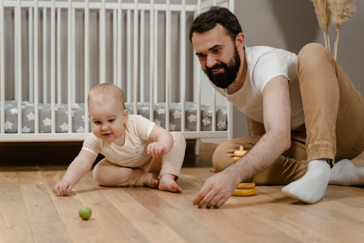 Man Sitting On Wooden Floor With His Baby