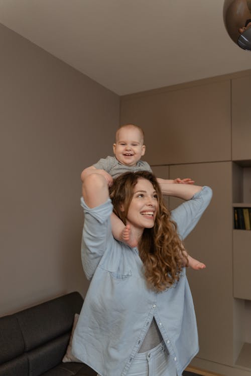 A Woman Carrying Her Baby Boy on Her Shoulders