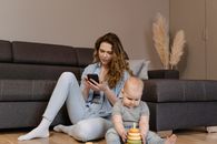 Woman in Gray Long Sleeve Shirt and White Pants Sitting on Gray Couch