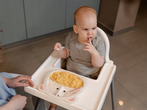 High Angle Photo of Child Eating Baby Food