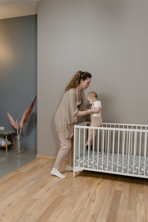 Free A Woman Putting Her Baby on the Crib Stock Photo