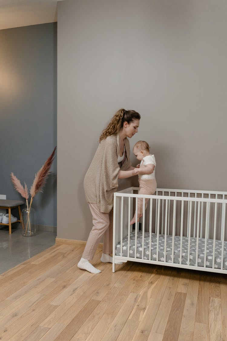 A Woman Putting Her Baby On The Crib