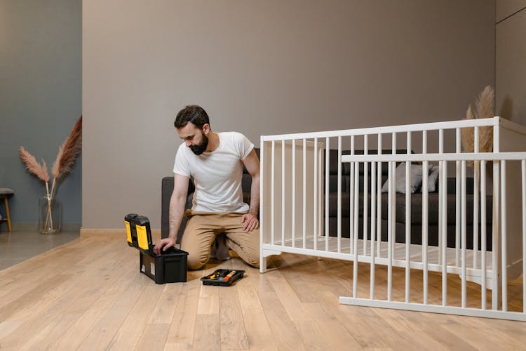 A Man In A White Shirt Building A Crib