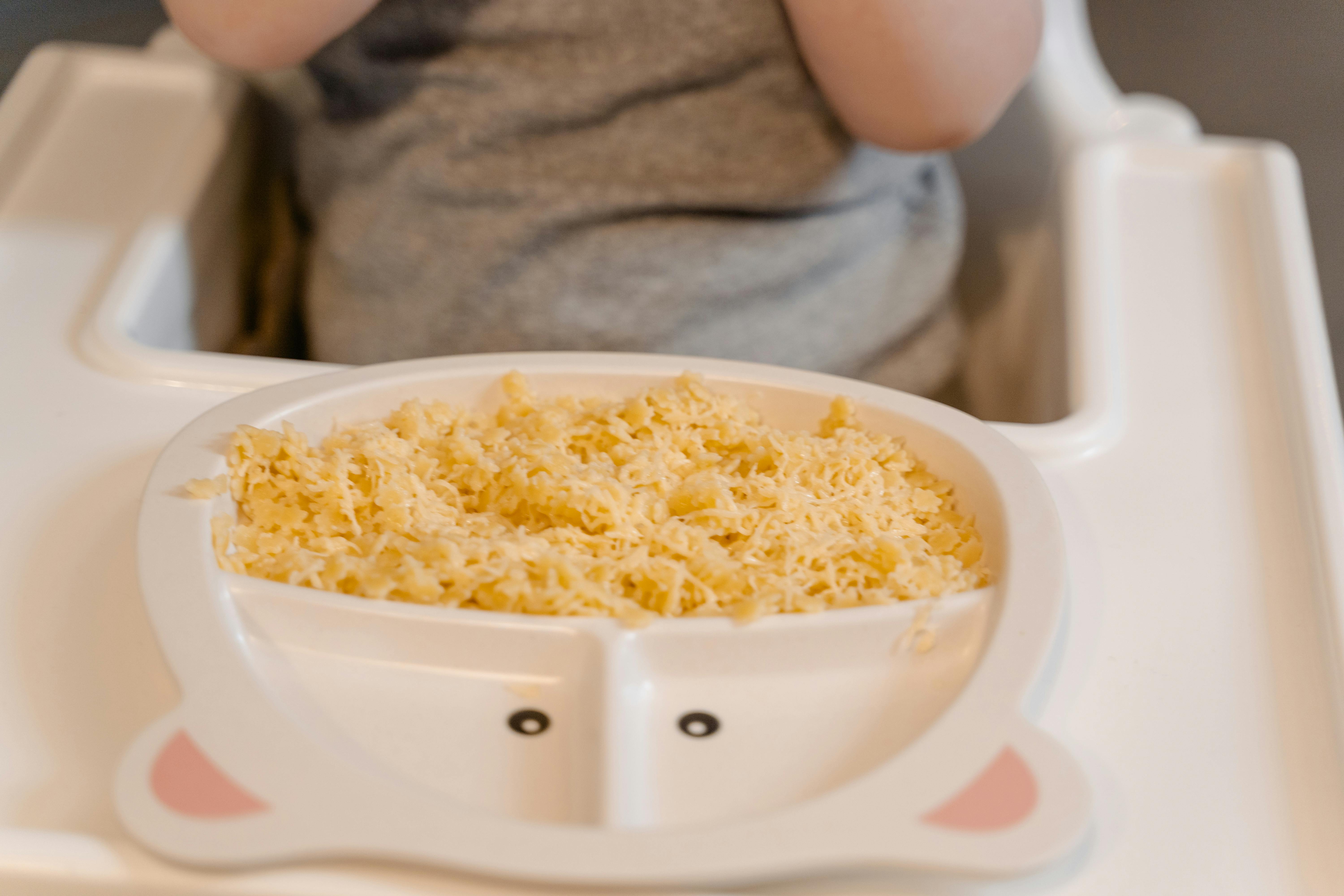 person holding white ceramic bowl with yellow rice