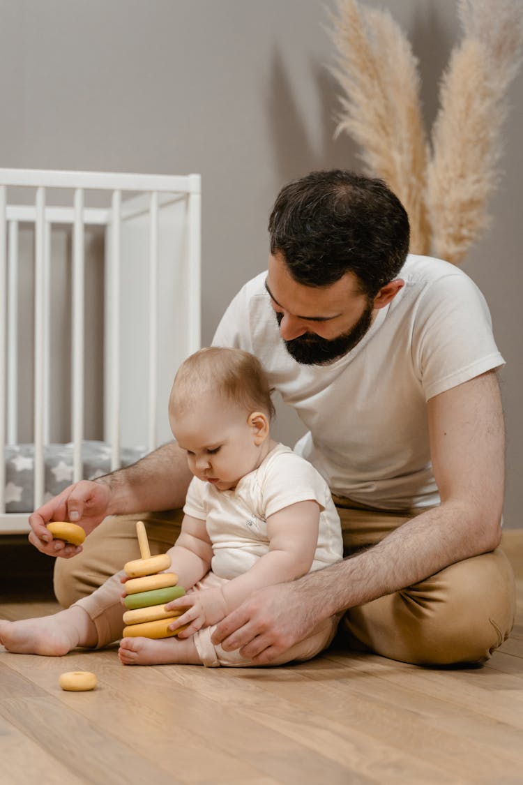 A Man Playing With His Baby While Sitting On The Floor