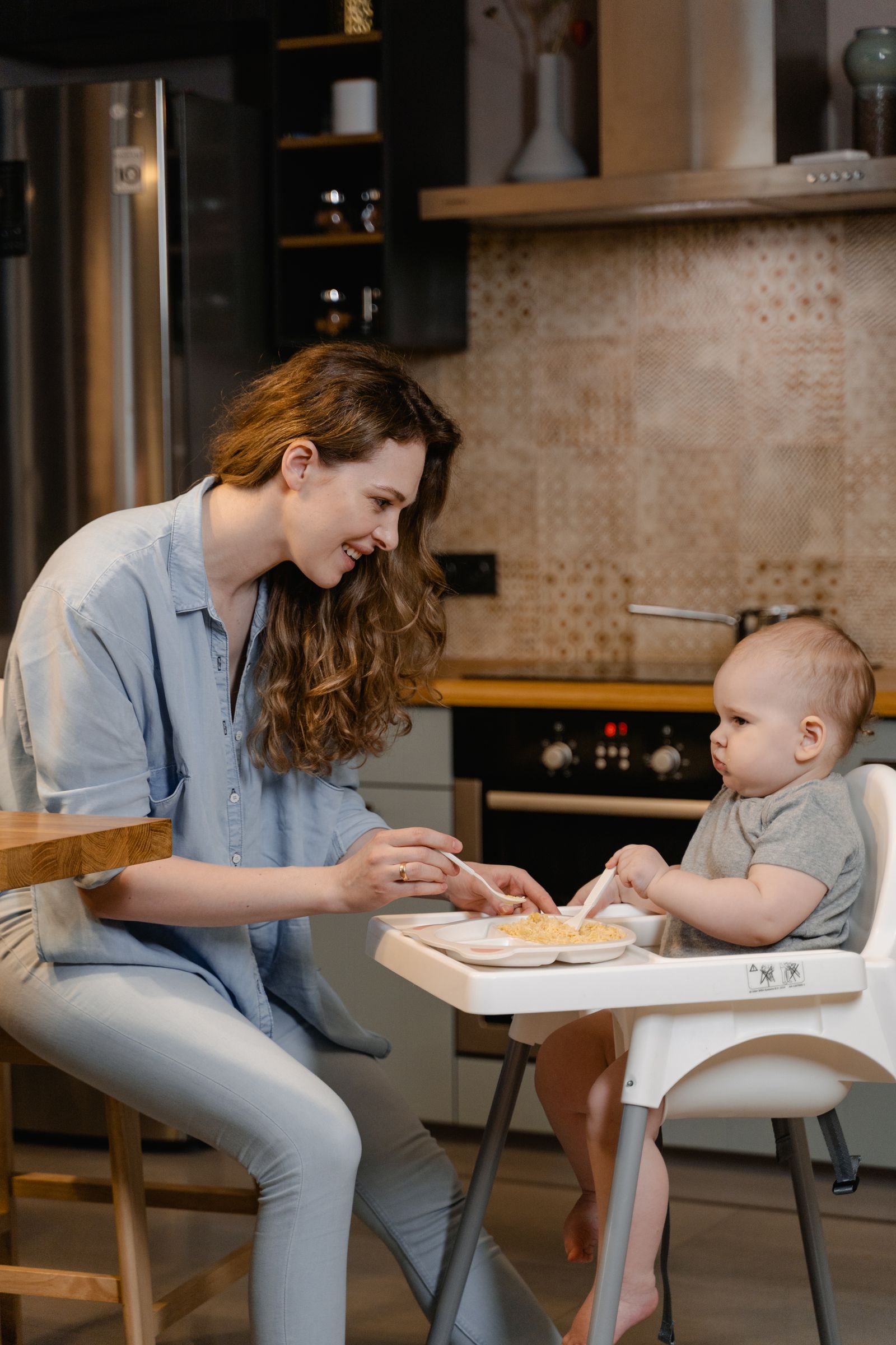 Mother feeding her baby in a warm home kitchen