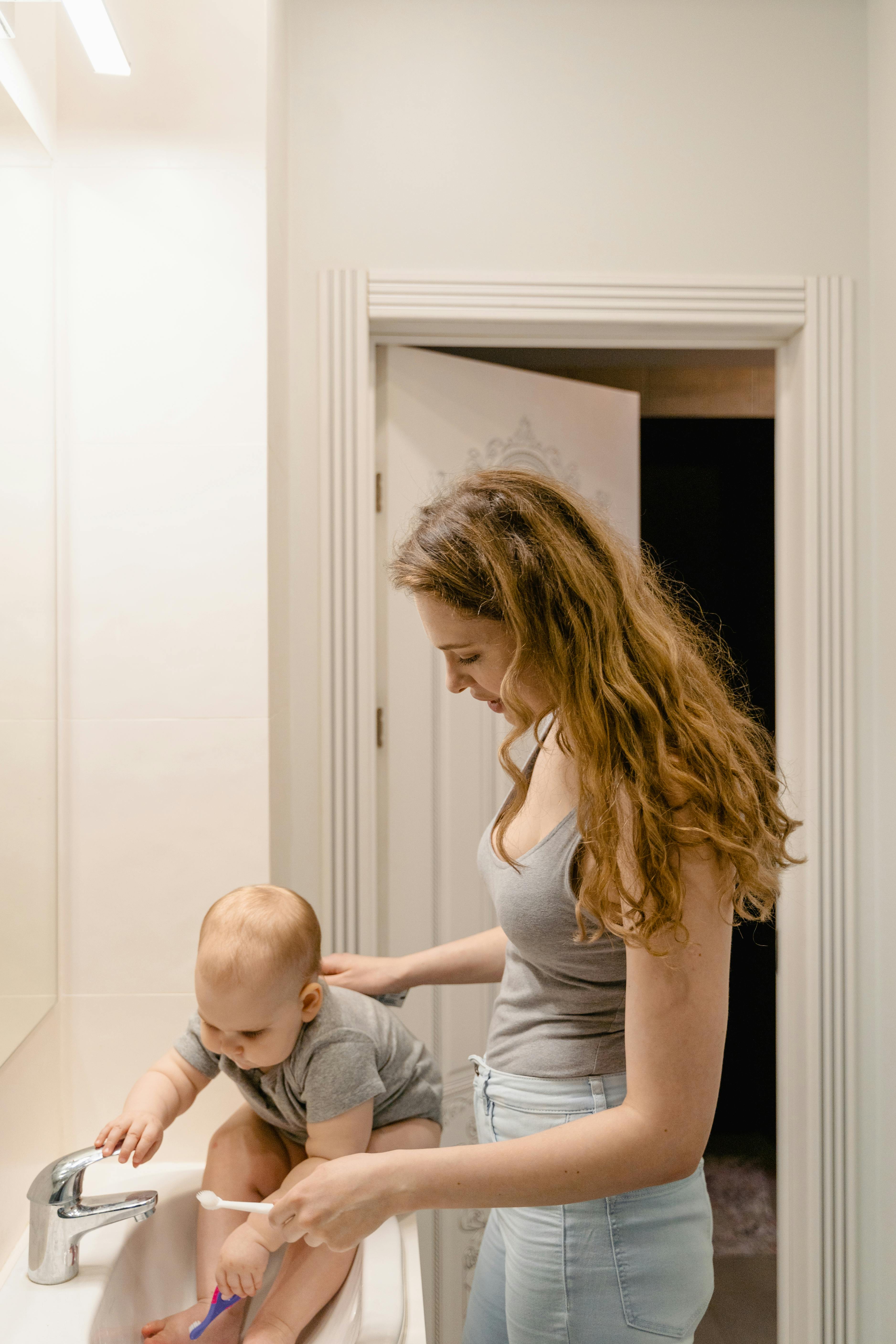 woman in gray tank top carrying baby in blue denim jeans