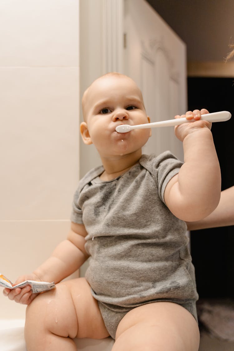 Photograph Of A Baby Brushing His Teeth