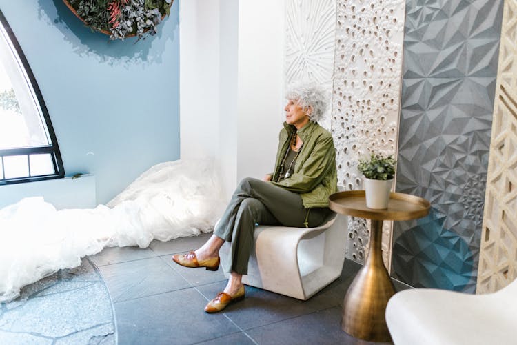 
A Woman In A Green Outfit Sitting On A Chair