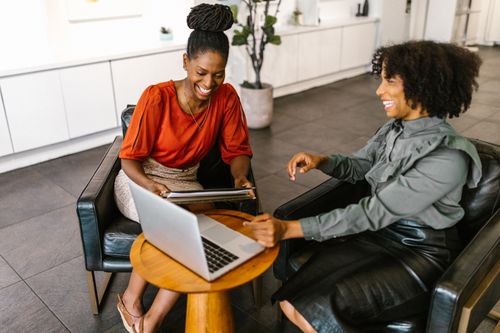 Free Two businesswomen in a modern office environment discussing work over a laptop. Stock Photo