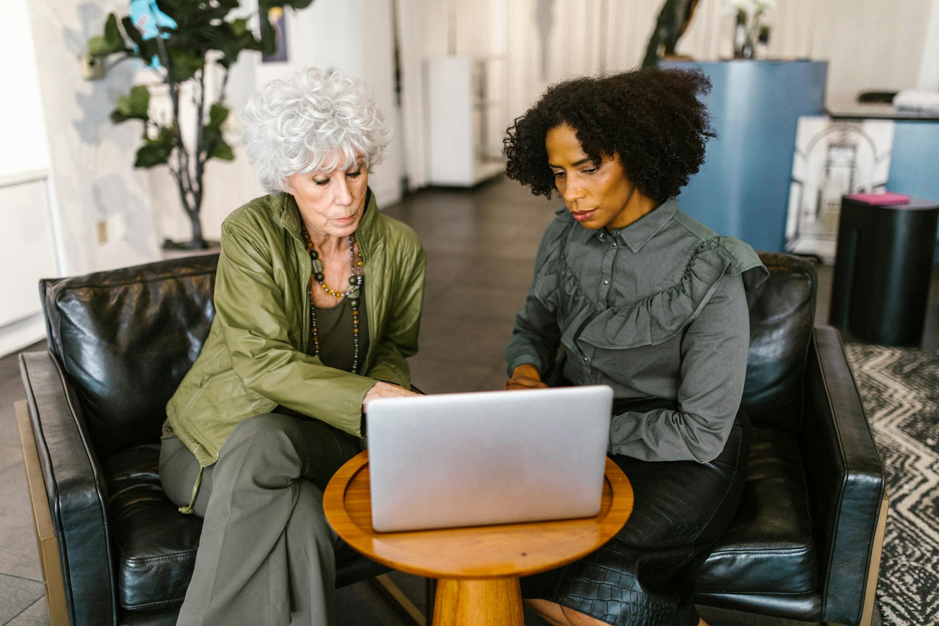 Two women discussing business plans on a laptop in a modern office.