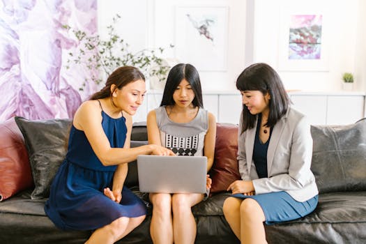 Three businesswomen collaborating on a laptop in a stylish, modern office.