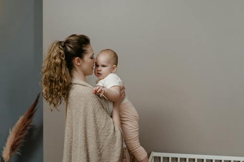 Женщина в сером свитере с младенцем