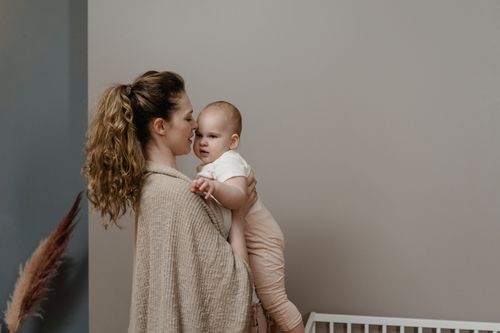 Free A mother lovingly holds her baby in a serene home interior, exuding warmth and care. Stock Photo