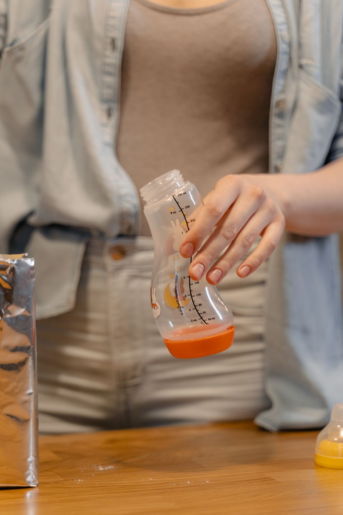 Parent preparing a baby bottle at a clean kitchen counter