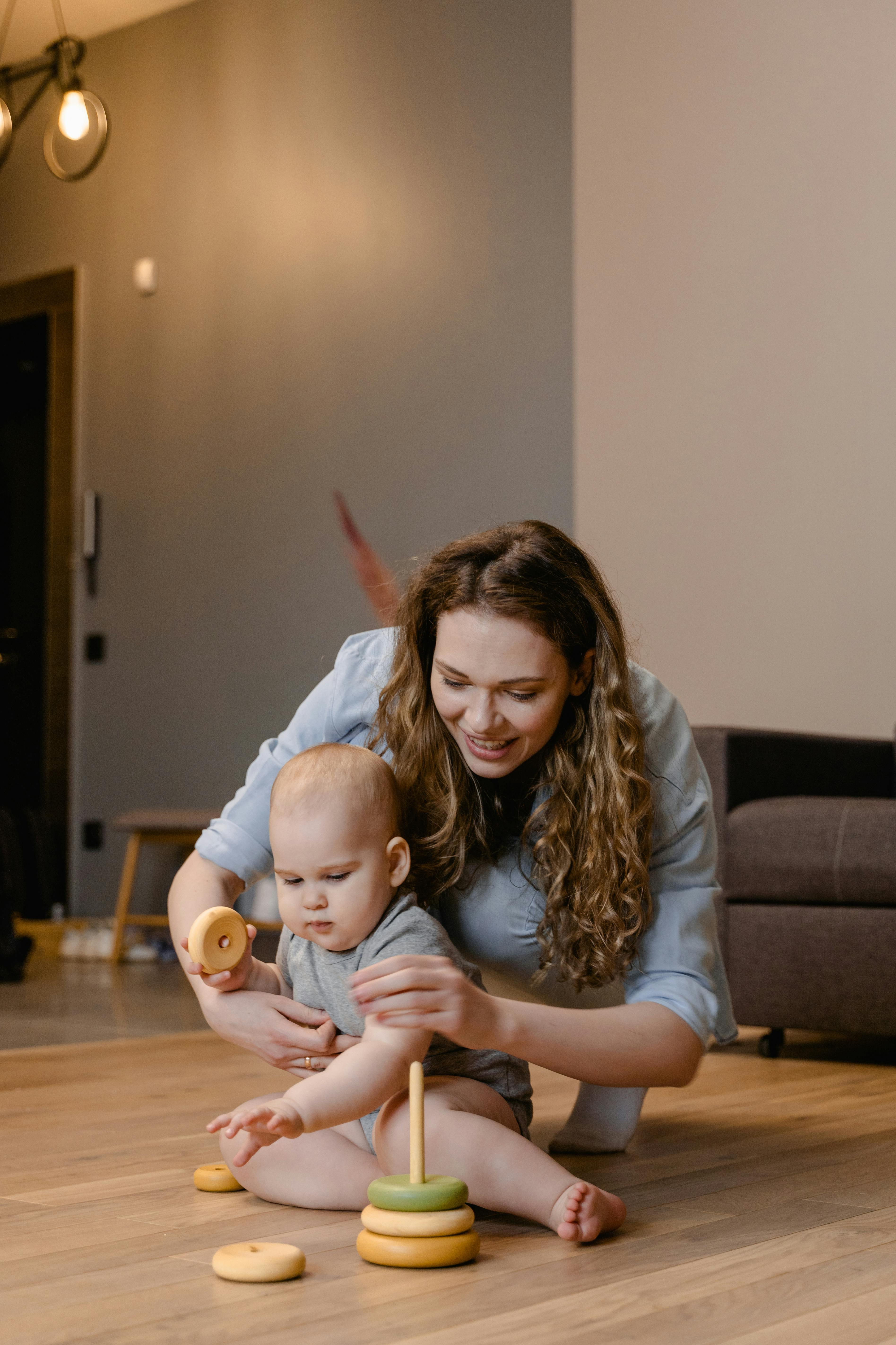 a woman playing with her baby while sitting on the floor