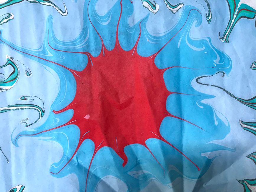 A vibrant abstract art piece featuring a red burst surrounded by swirling blue patterns, showcasing fluid art technique.