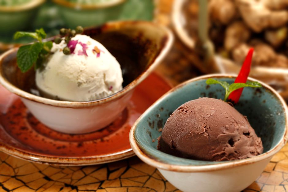 Close-up view of gourmet chocolate and vanilla ice cream served in decorative bowls with garnishes.