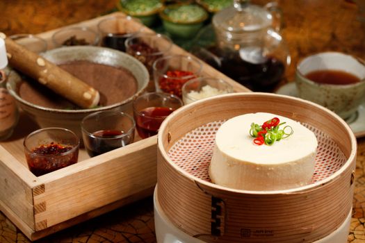 A beautifully arranged Asian steamed tofu dish with spices and condiments, perfect for gourmet dining.