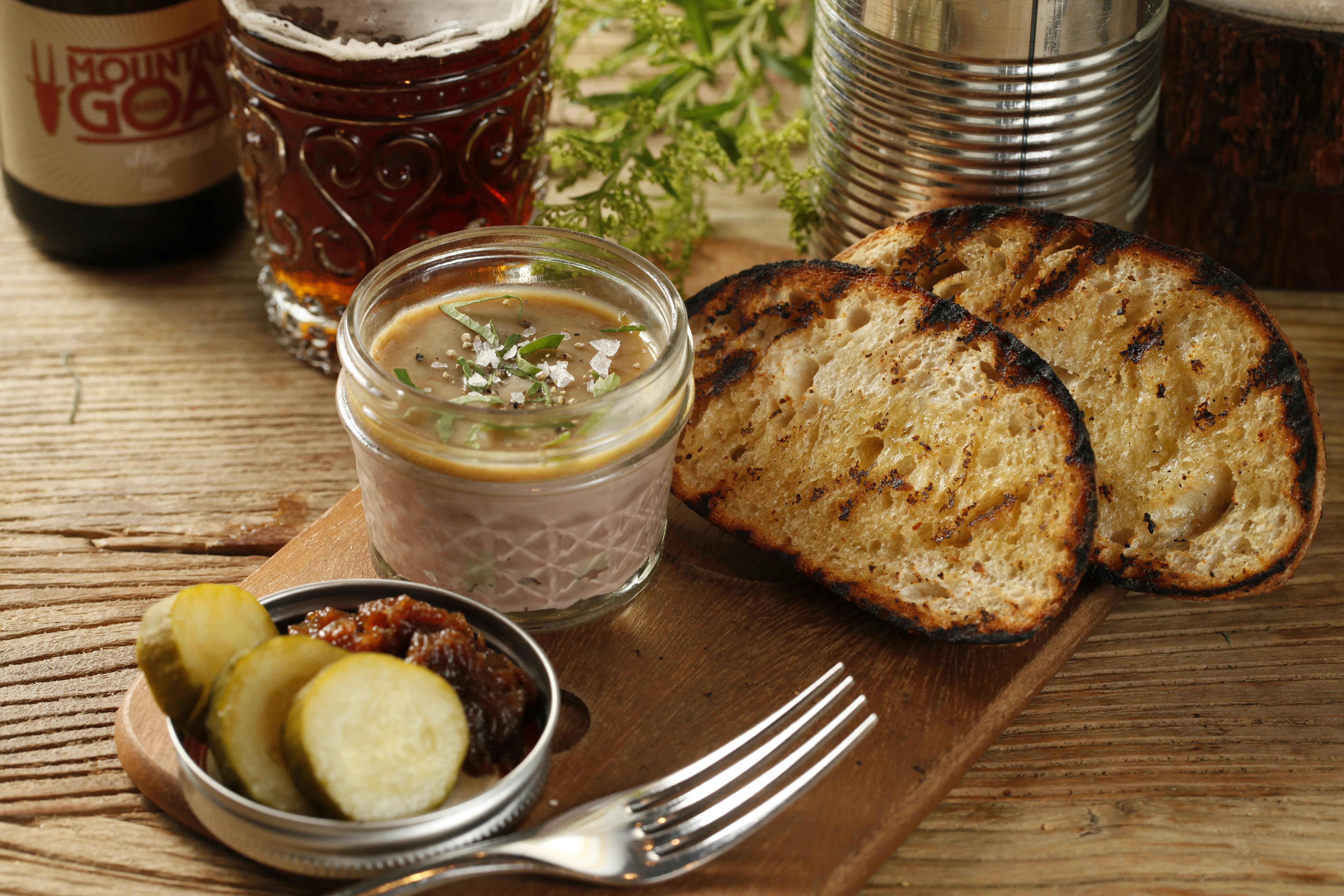 Finished vinegar from fruit scraps in glass jar - Delicious pate served with pickles and grilled bread on a wooden table, perfect 