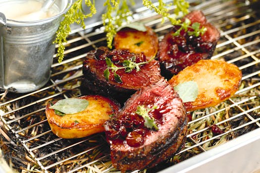 Juicy grilled steak with potatoes and herbs on a rustic barbecue grill.