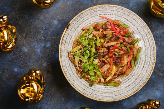Colorful Vietnamese noodle dish with golden lucky cats on a textured surface.
