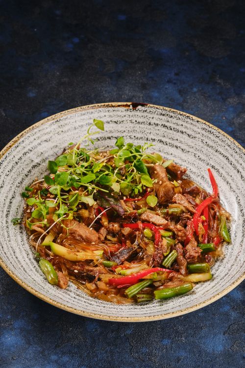 Free Delicious stir-fried noodles with beef, peppers, and greens in a traditional Chinese style. Stock Photo