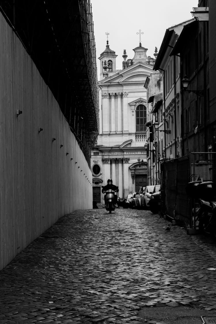 Anonymous Biker Driving Motorcycle Against Cathedral In Old Town