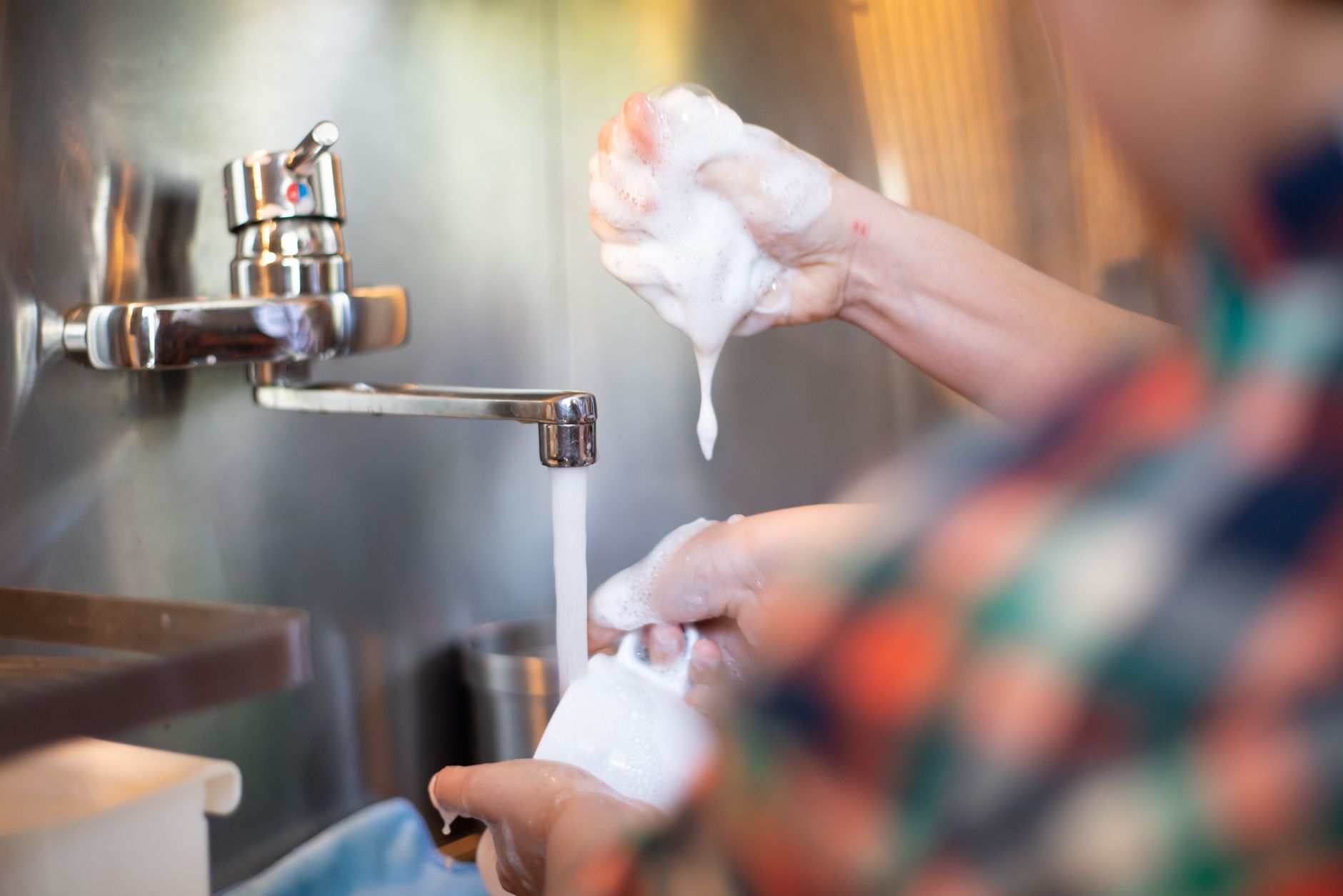 Detailed shot of hands washing with soap under water, emphasizing hygiene.