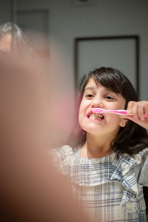 Girl in Checked Dress Brushing Her Teeth