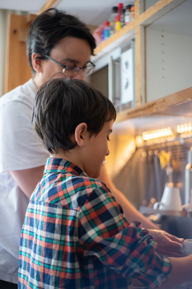 Father And Son Washing The Dishes In The Sink