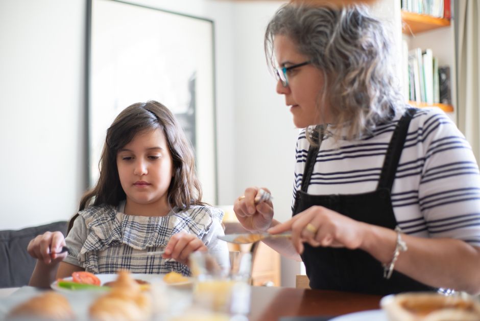 Una madre y su hija disfrutando de tiempo de calidad juntas en la mesa durante el día.