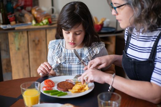 Elderly Woman teaching her Granddaughter Table Manners