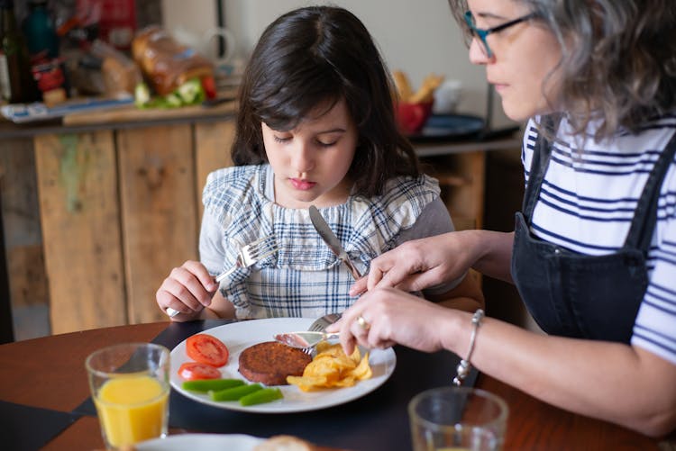 Elderly Woman Teaching Her Granddaughter Table Manners