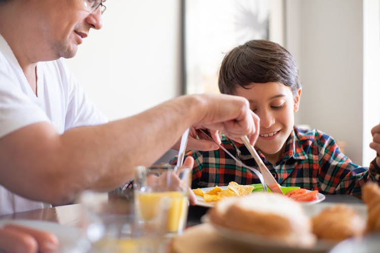 Photograph Of A Father Teaching His Son Table Manners