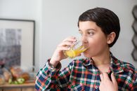 Boy in Red Blue and White Plaid Button Up Shirt Drinking Yellow Liquid from Clear Drinking