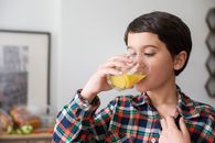 Woman in Red White and Black Plaid Dress Shirt Drinking Yellow Liquid from Clear Drinking Glass