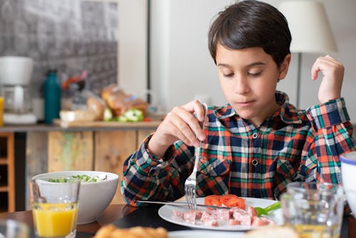 Free Kid in Plaid Long Sleeves Eating Breakfast Stock Photo