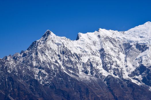 A stunning view of snow-covered mountain peaks under a vibrant blue sky, perfect for outdoor enthusiasts.