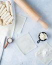 Uncooked Spring Rolls in Plastic Container Beside a Rolling Pin and Wrapper